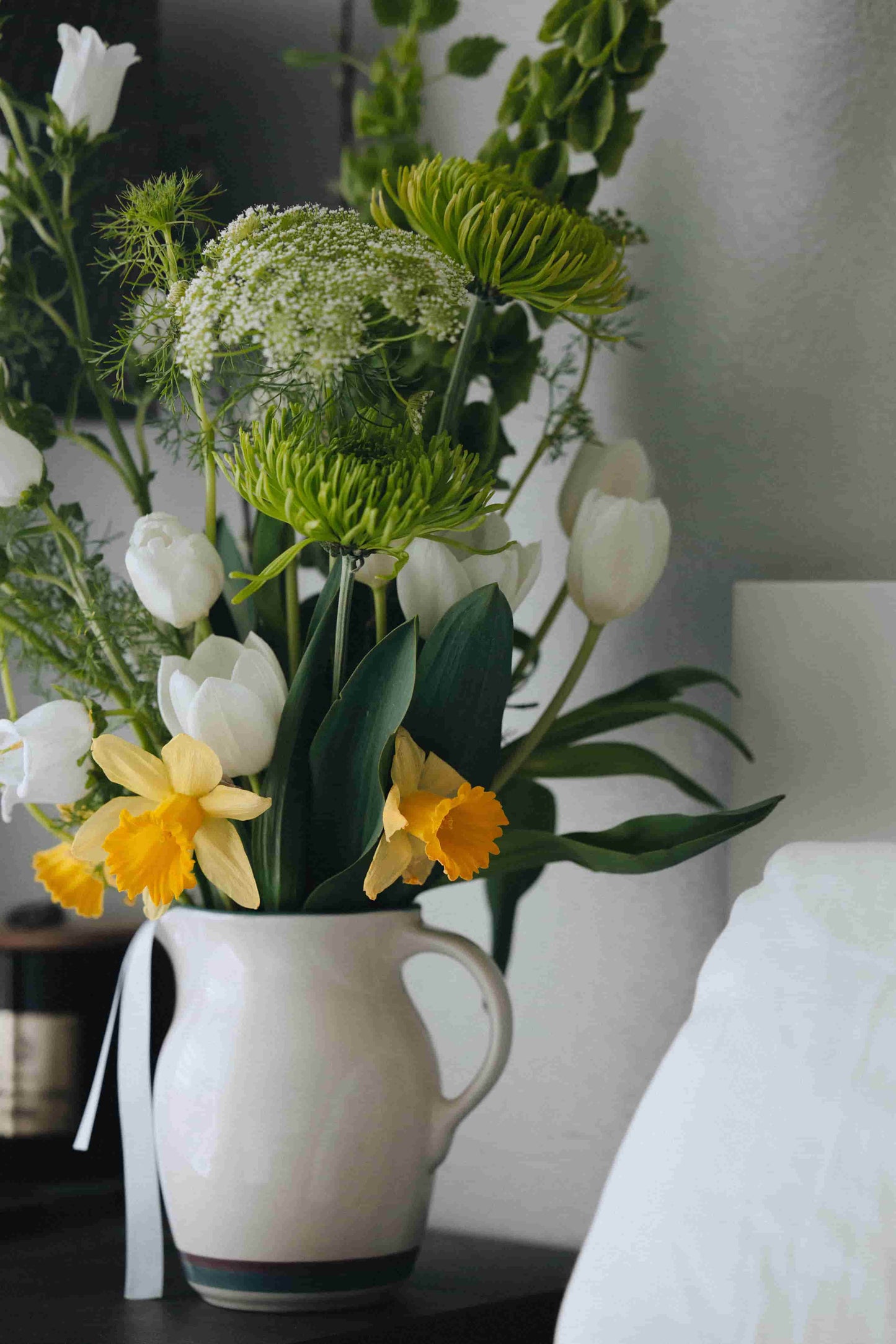 Spring flower bouquet on nightstand with tulips, bells of Ireland and daffodils – flower subscription by Kvetka