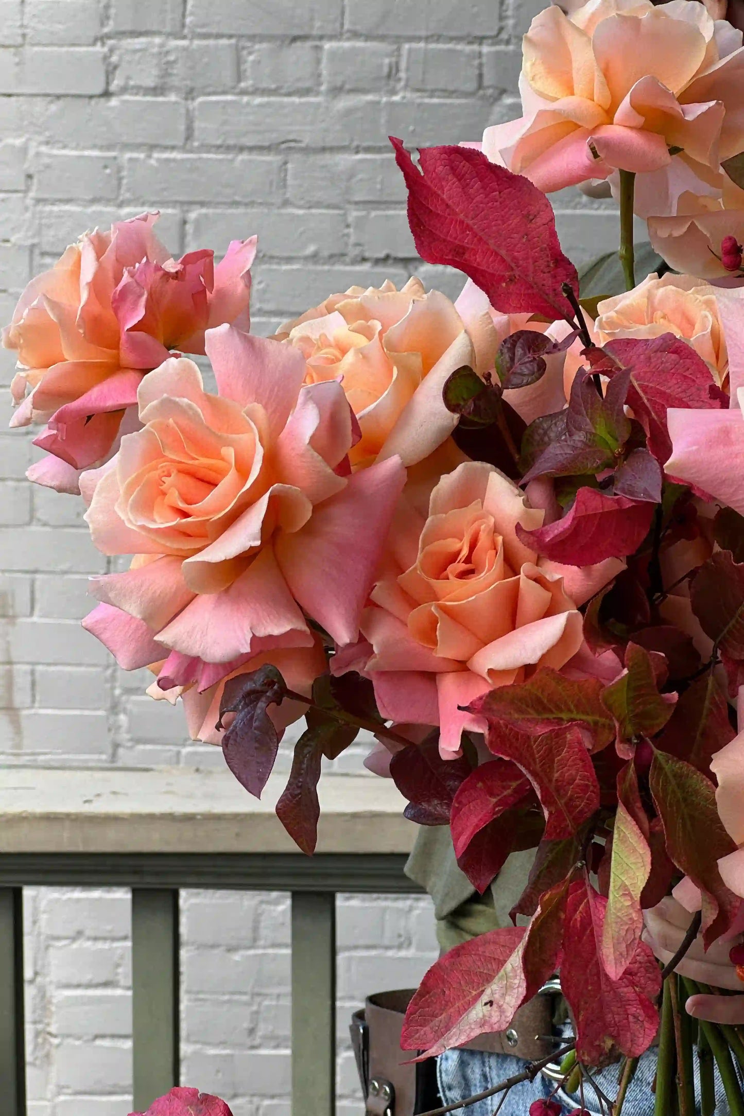 Fresh seasonal bouquet with peach roses and burgundy foliage by Kvetka Flower for same-day delivery