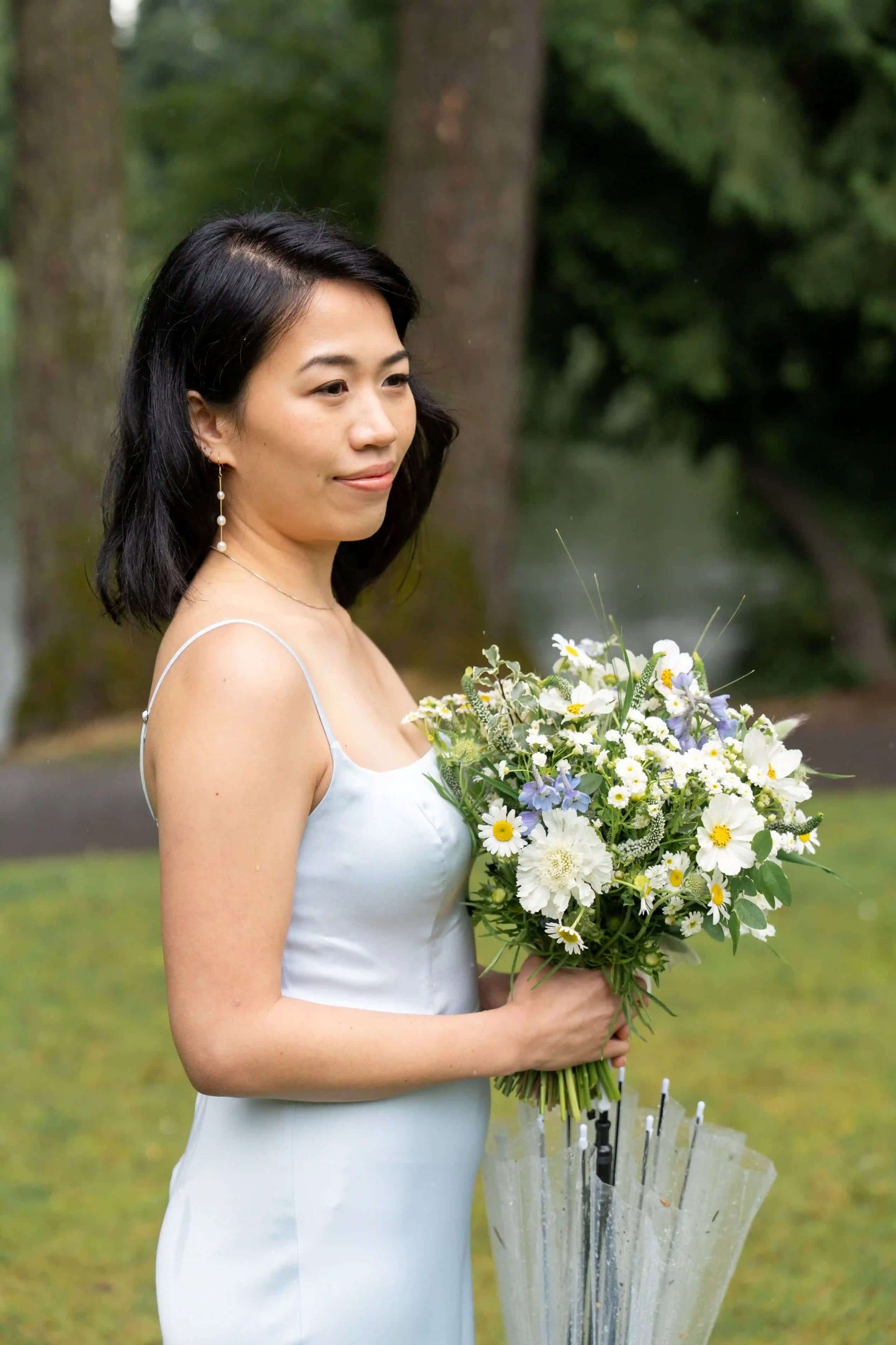 Bridesmaid holding a delicate white and blue bouquet by Kvetka Flower with chamomile flowers
