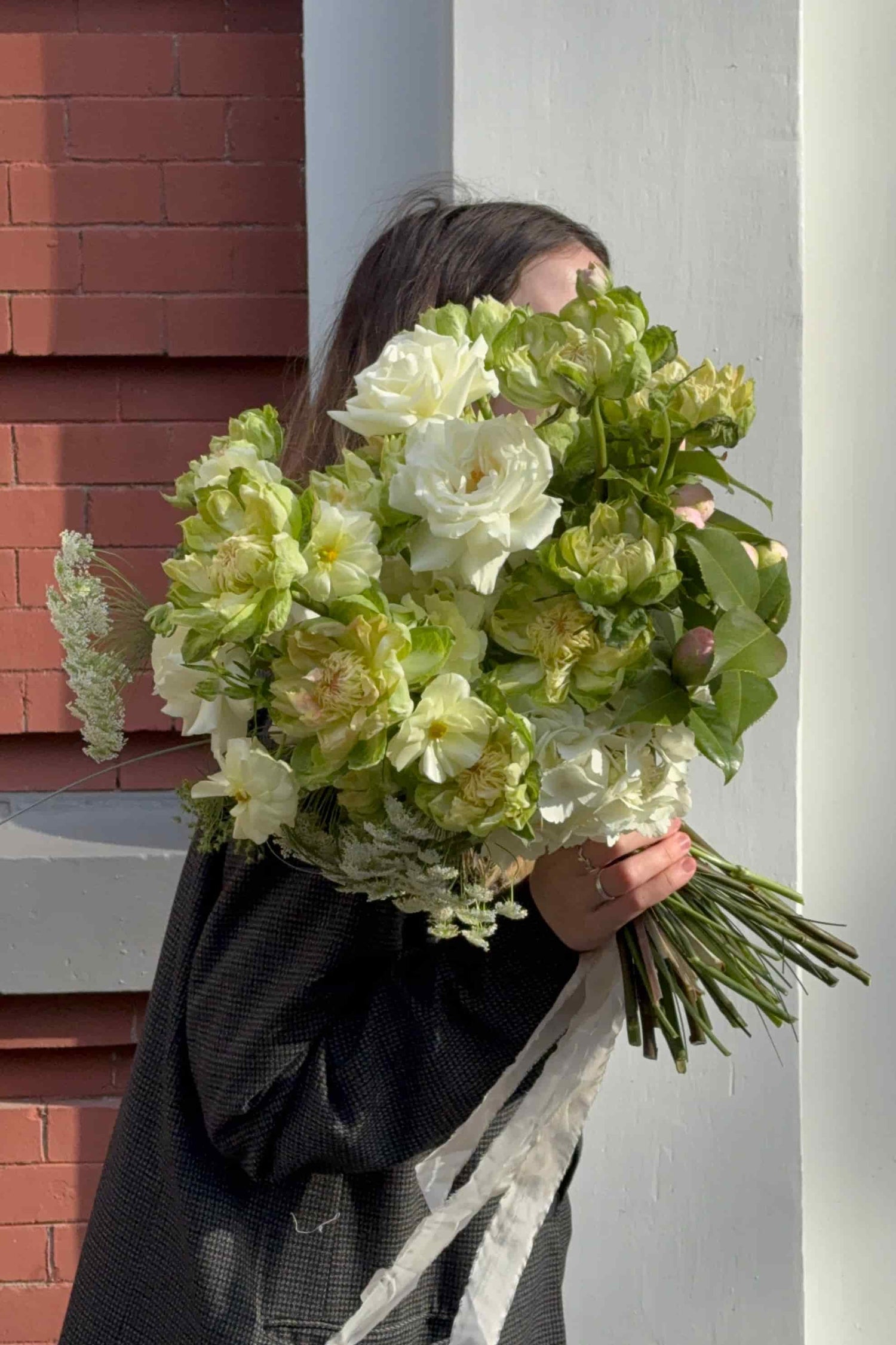 Person holding a large European-style hand-tied bouquet of white and green veggie roses and butterfly ranunculus, by Kvetka Flower
