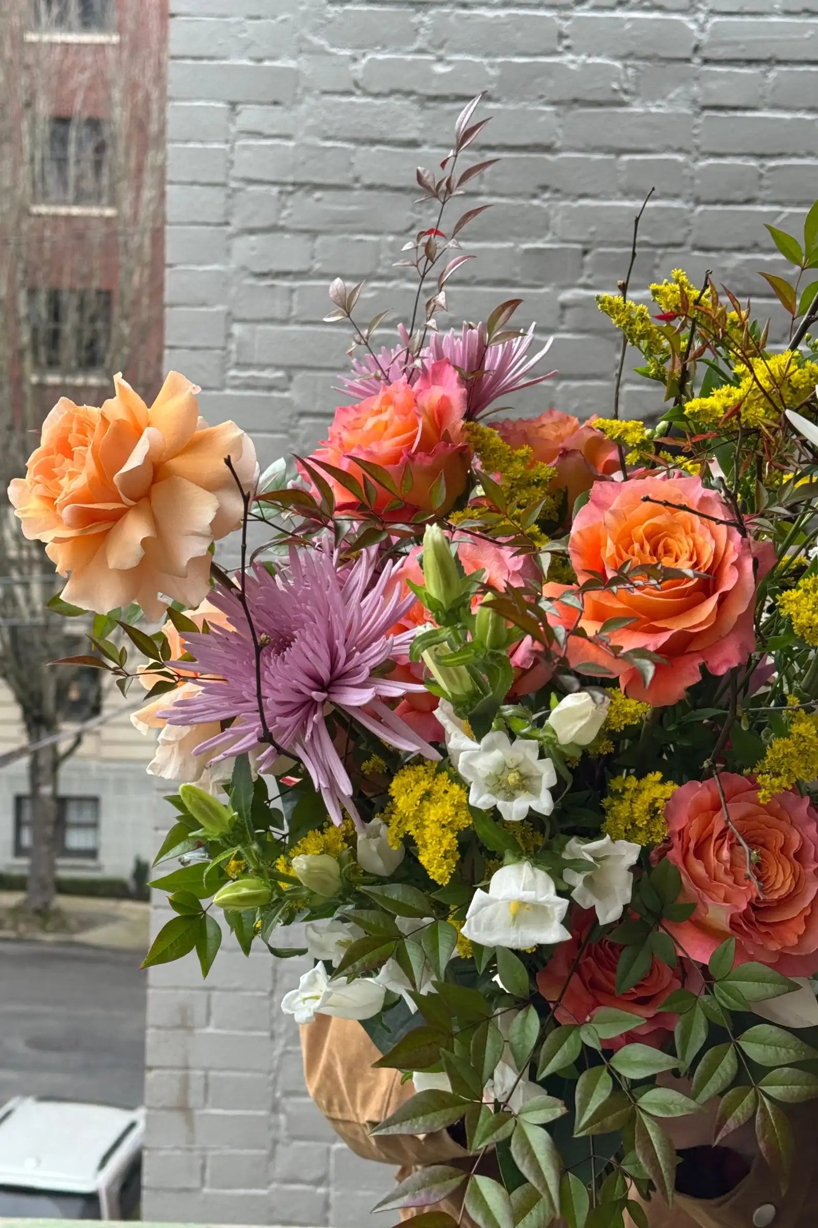 Detail of large seasonal bouquet orange roses lavender mums lush greenery Kvetka Flower