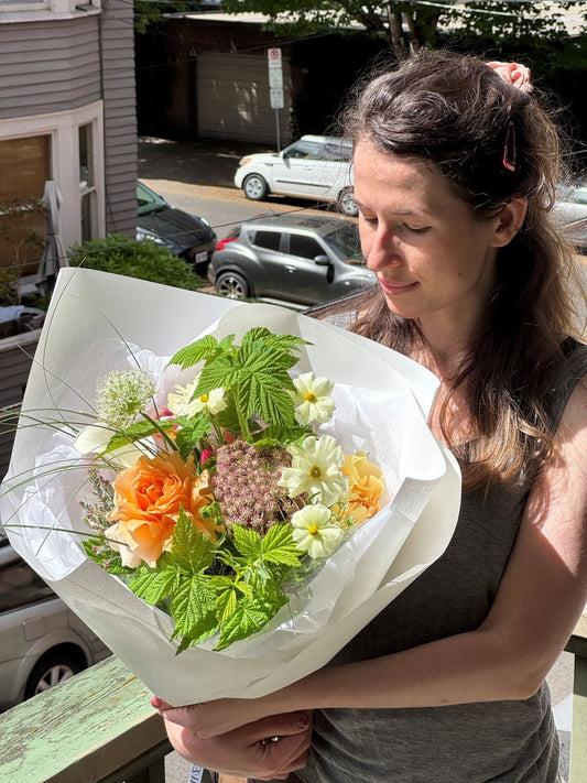 Fresh seasonal summer bouquet with peach garden rose, ranunculus, allium, white calla lilies, and greenery by Kvetka Flower