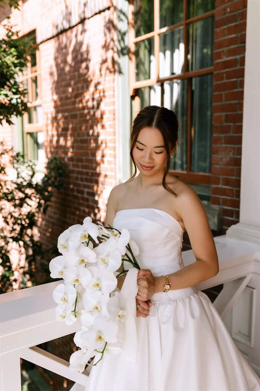 Bride holding cascading white phalaenopsis orchid bouquet by Kvetka Flower at McMenamins Edgefield