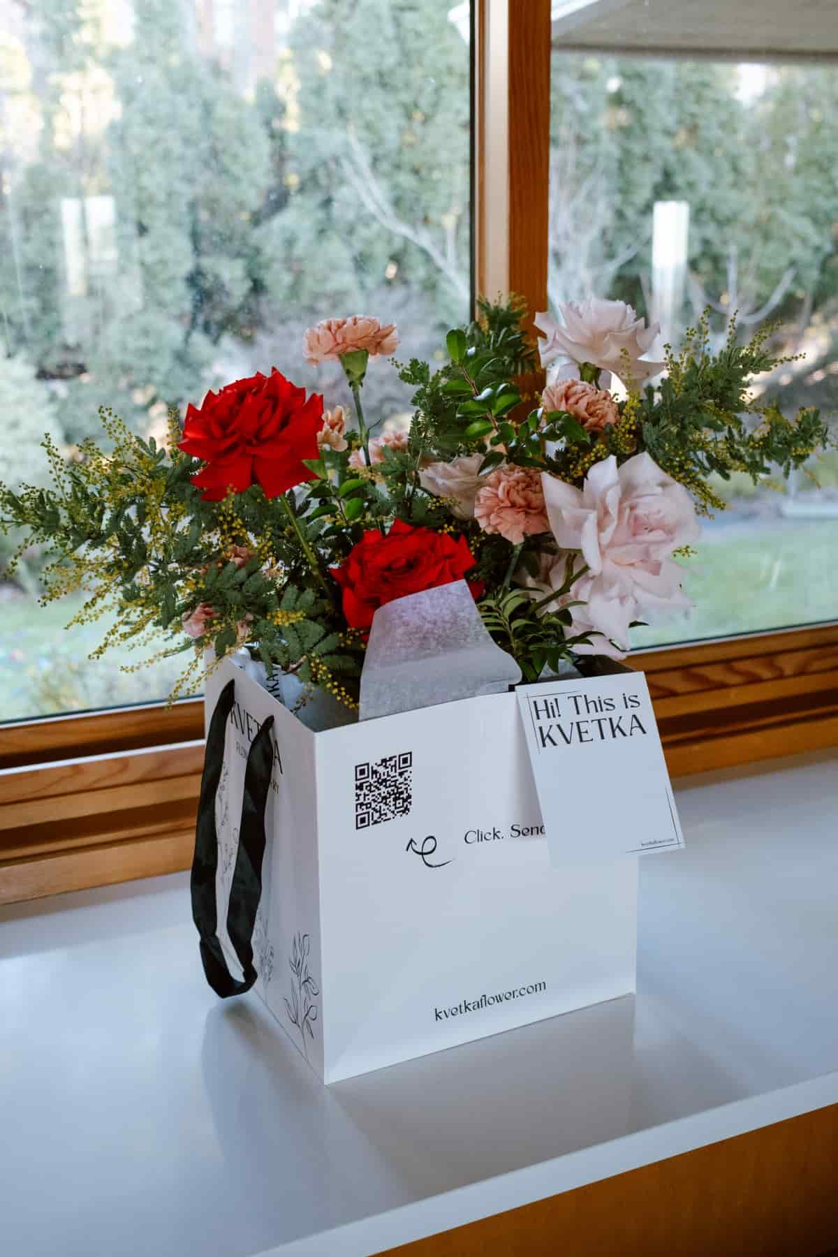 Branded white Kvetka signature flower box holding red and pink roses, carnations and mimosa, by Kvetka Flower