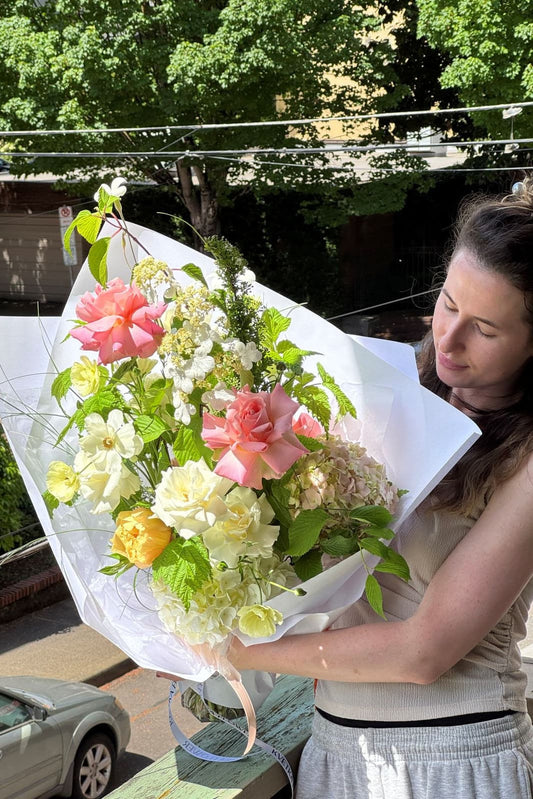 Woman holding Pink Acacia pink rose bouquet with yellow and white seasonal accents by Kvetka Flower