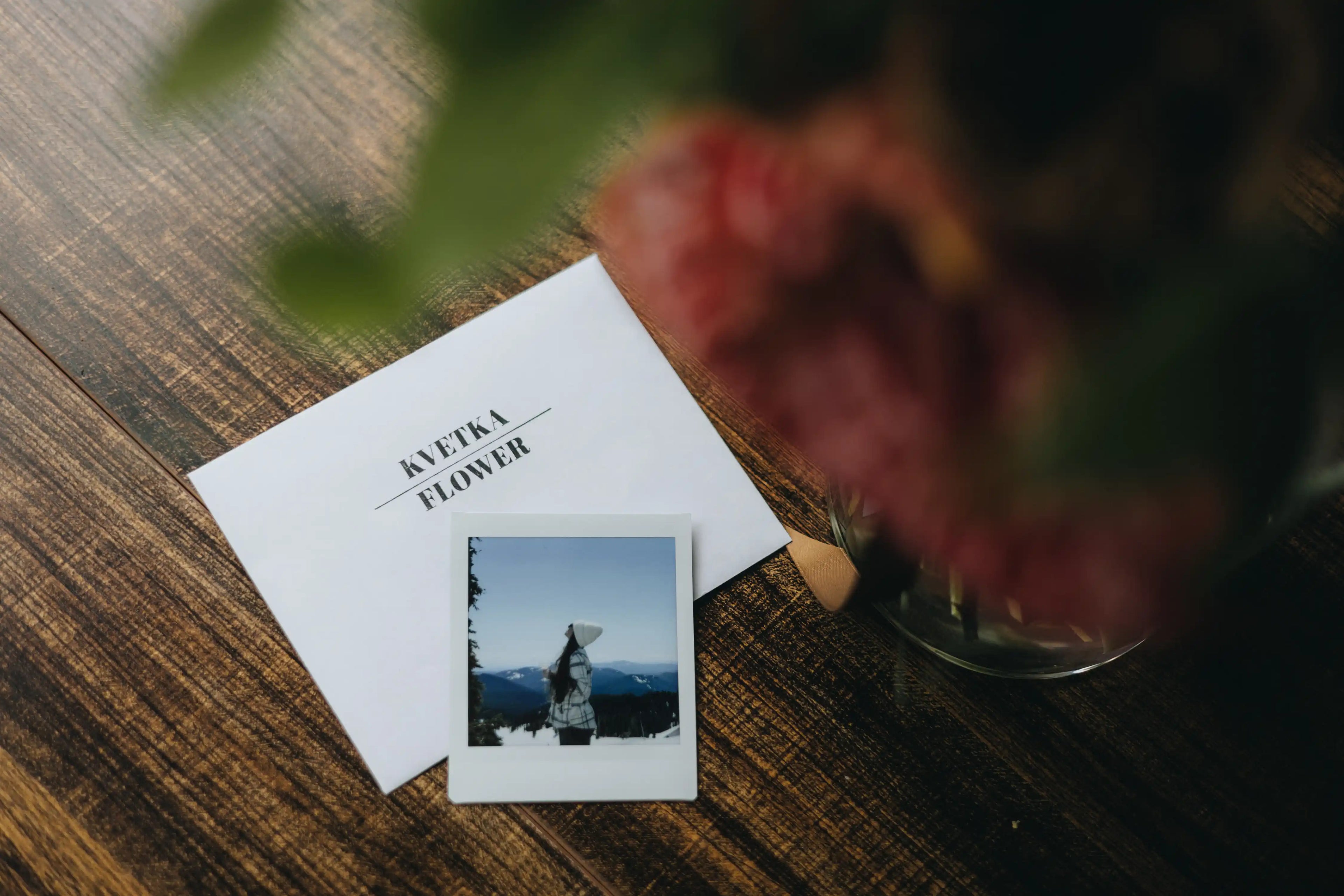 Polaroid photo on a table next to Kvetka Flower card and bouquet — a free add-on with flower delivery in Austin, TX.